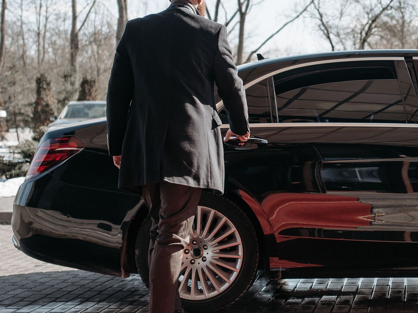 Chauffeur loading luggage into the boot of a saloon
