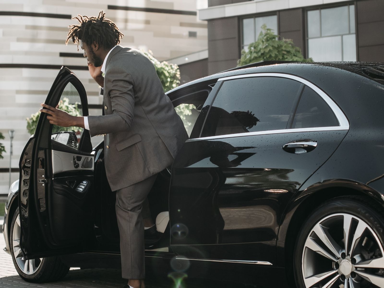 Passenger in a suit stepping into a black Mercedes saloon