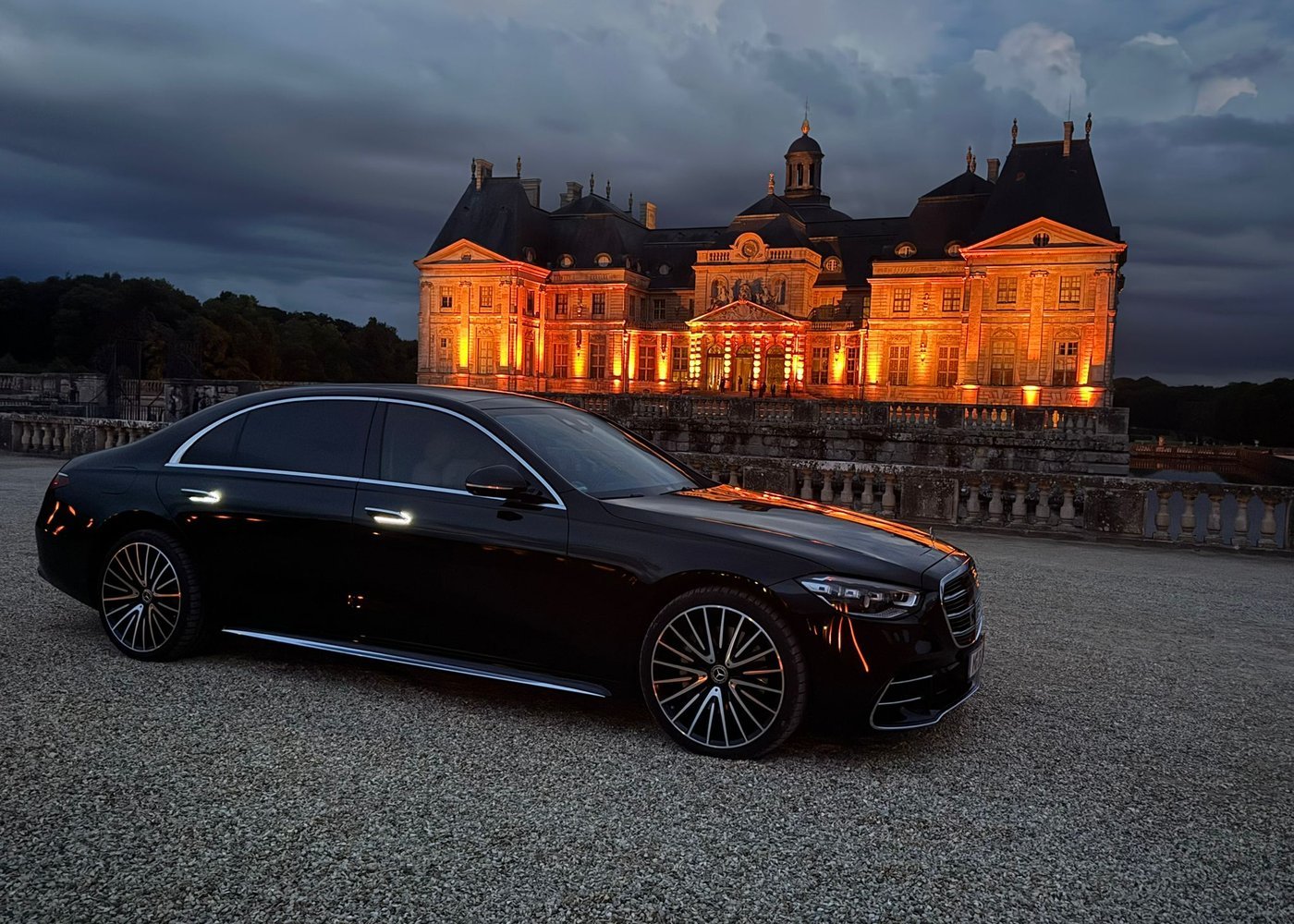 Mercedes S-Class in front of a floodlit French château at dusk
